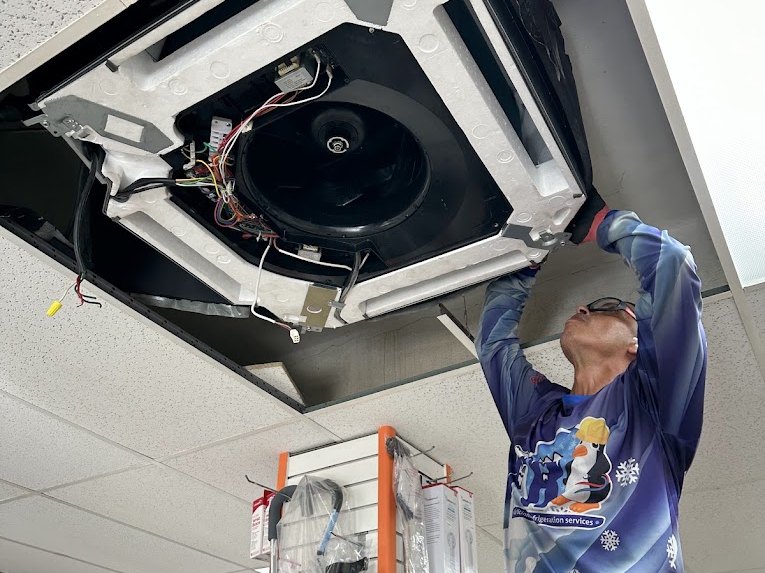 Félix servicing a ceiling-cassette unit inside a local business